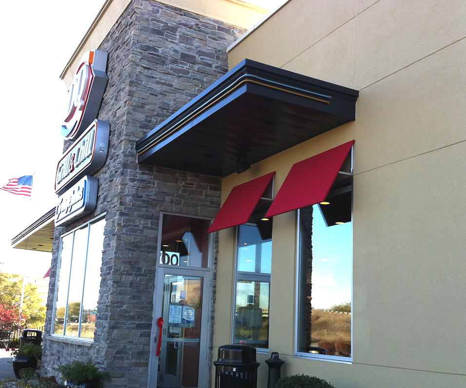 Side photo of Dairy Queen Building showcasing red awnings over windows